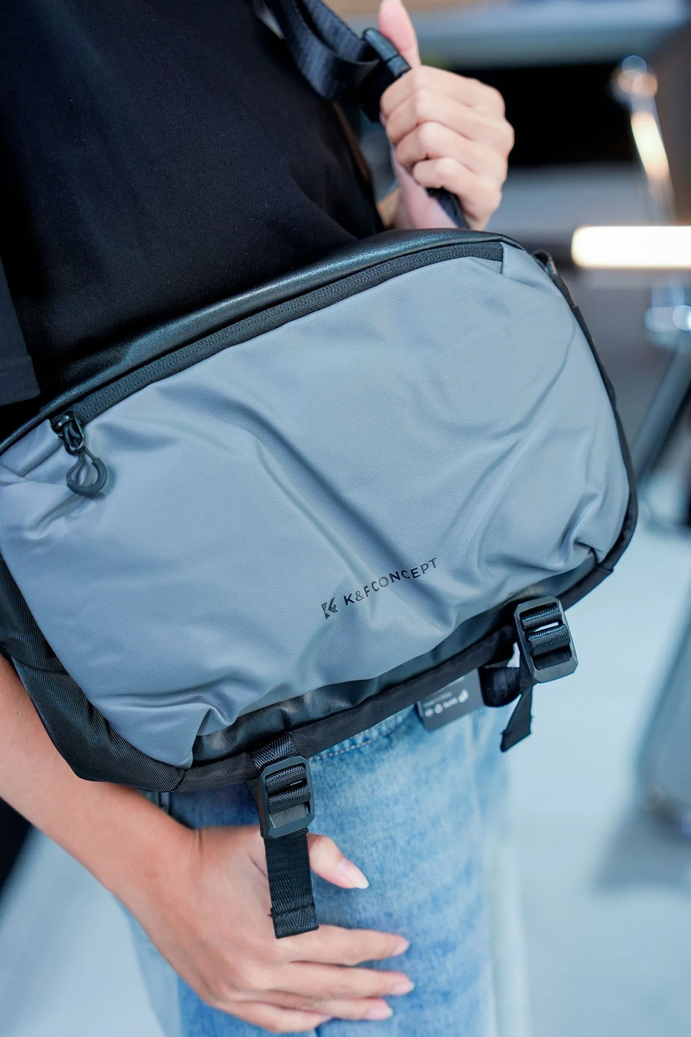 A close view of a gray bag with straps held beside jeans