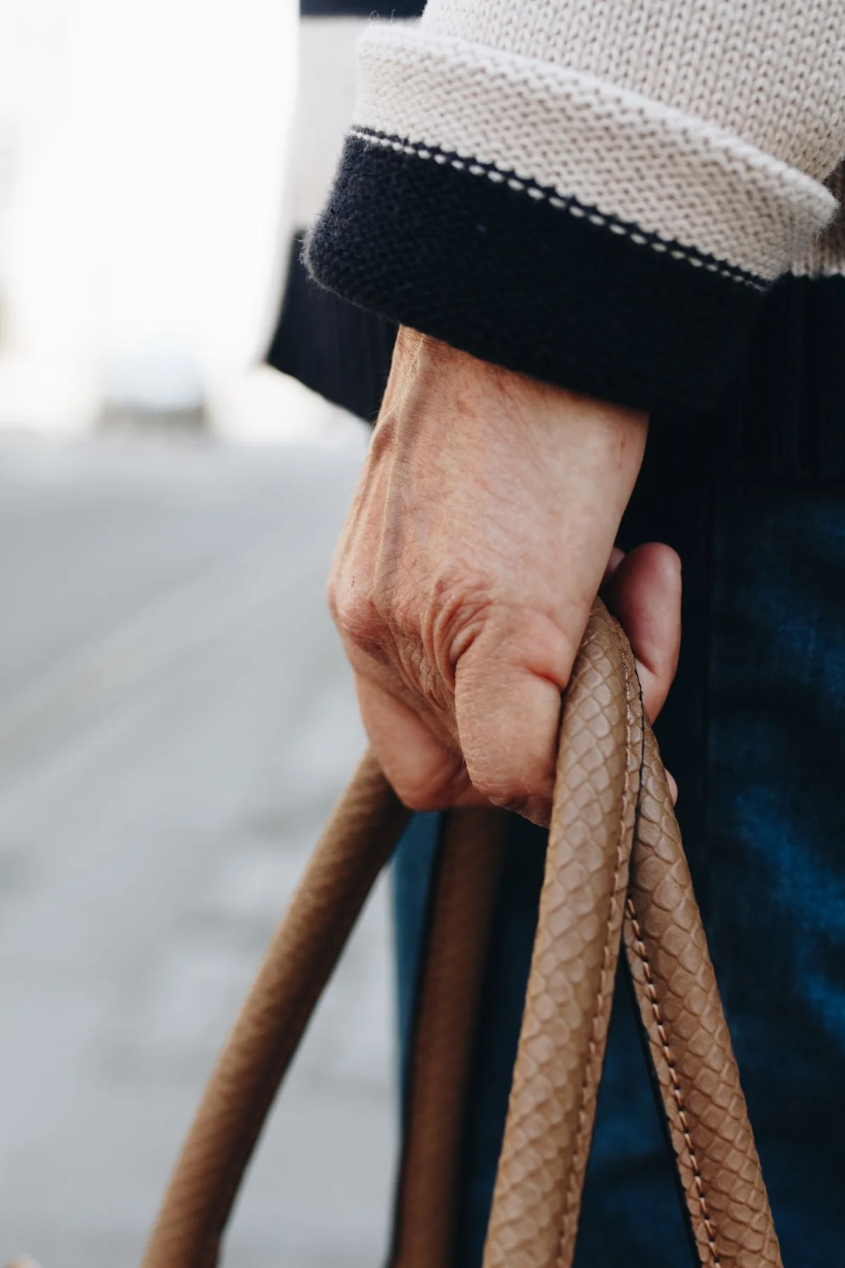 A close view of a hand holding a textured brown bag beside a dark sleeve