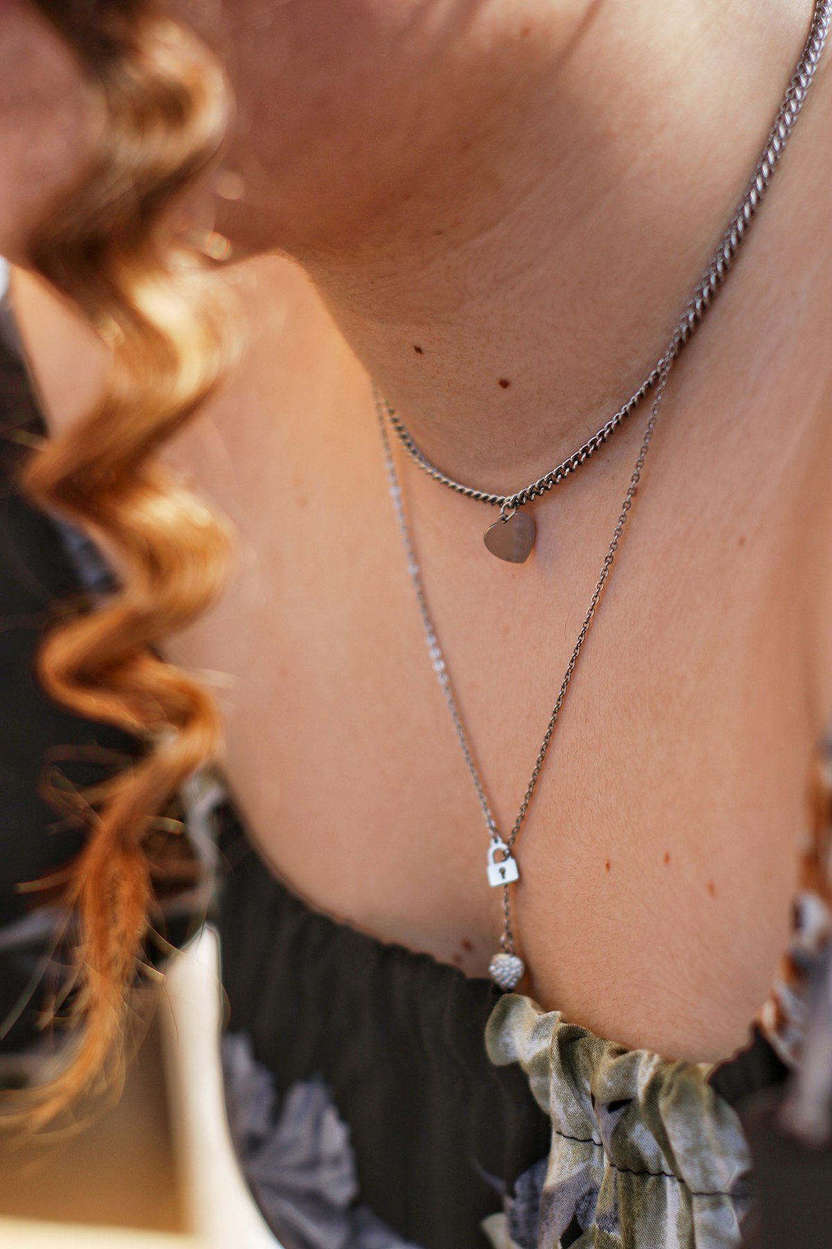A close view of layered necklaces beside a pale shirt neckline