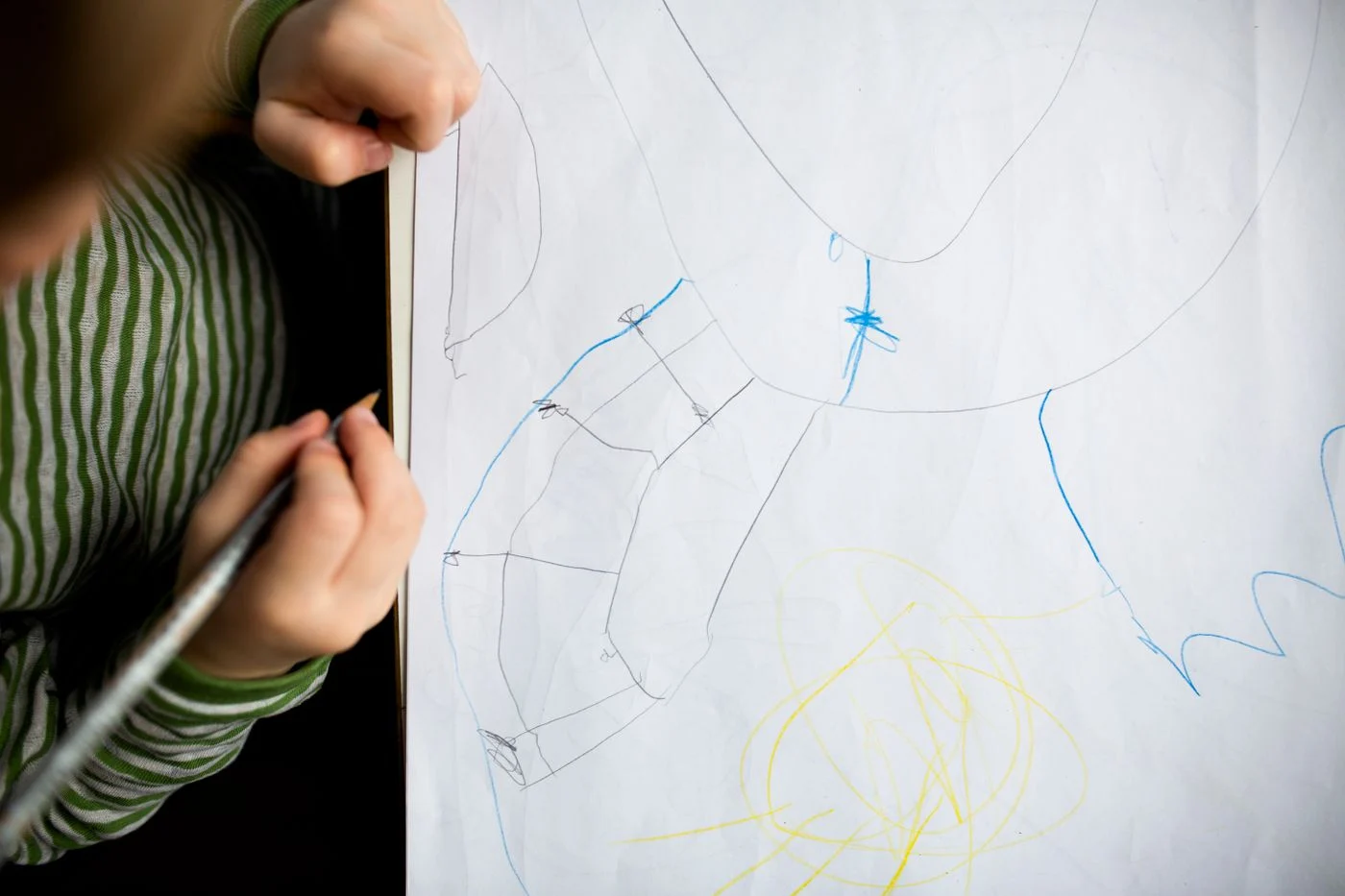 Child drawing with crayons on a large sheet of paper