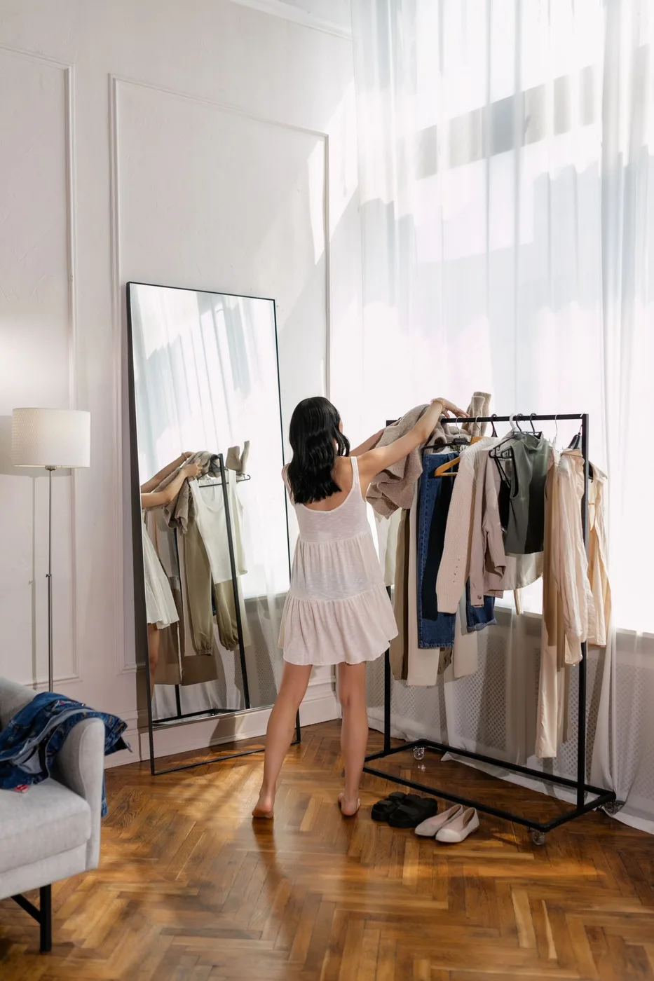 Woman arranging clothes on a clothing rack in a bright room