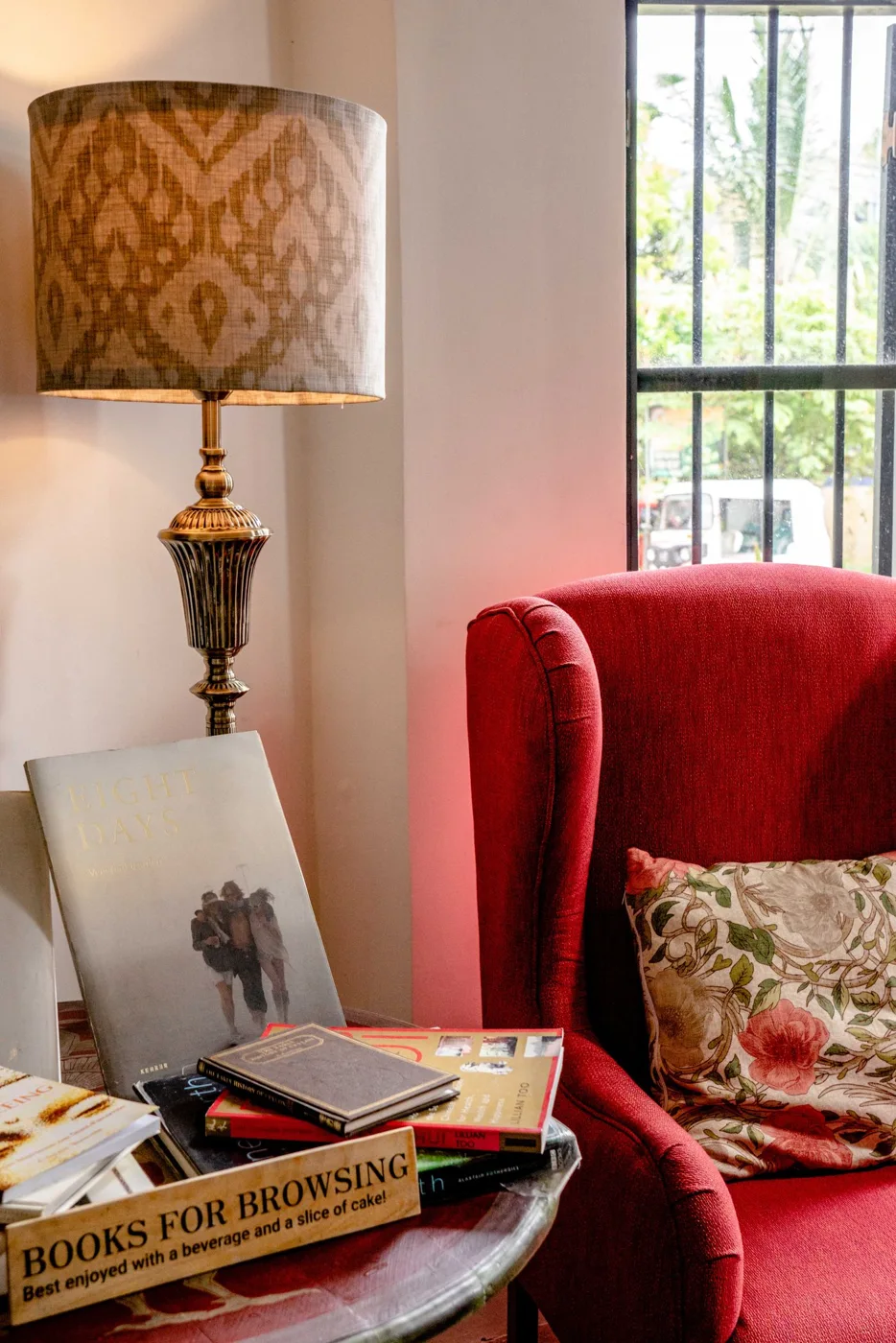 Red upholstered armchair beside a table, lamp and framed picture