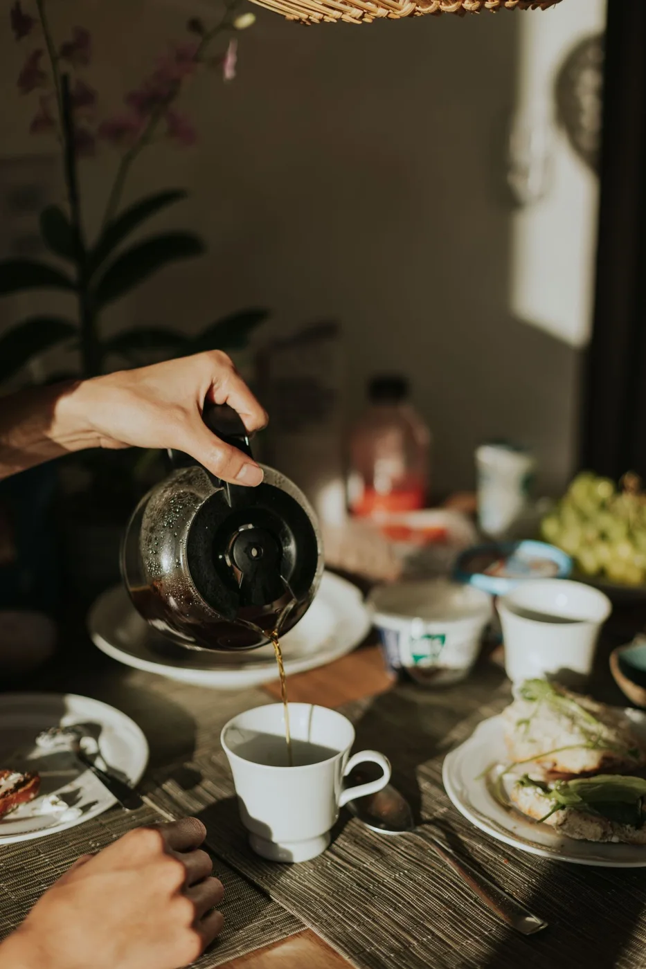 Coffee being poured from a glass pot into a cup on a table