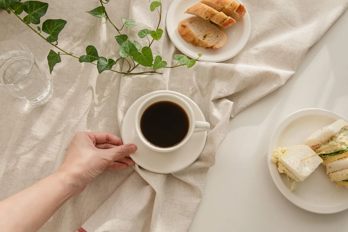 Coffee, bread and plates on a pale tablecloth
