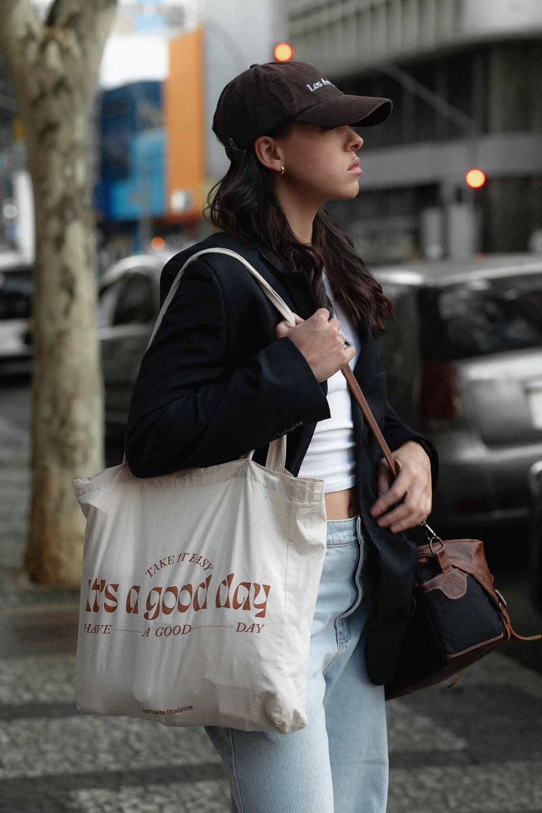 Woman in casual layers walking with a tote bag