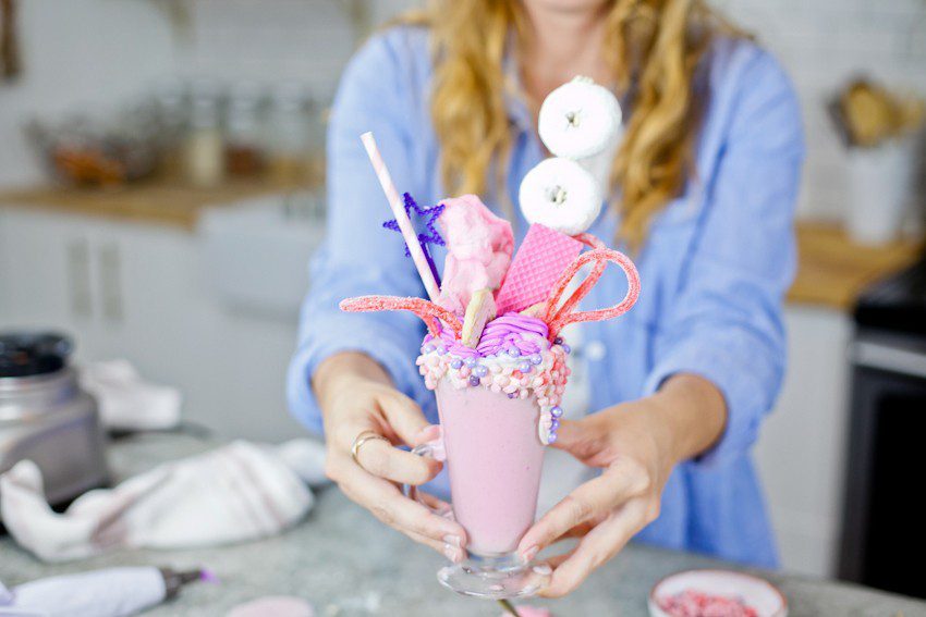 These Epic Royal Crazy milkshakes are indulgently MAGICAL! A rich, thick strawberry milkshake is topped with a sugaring of sprinkles and candies to make a delicious drink fit for a princess... or a prince. A pretty in pink and purple freak shake!