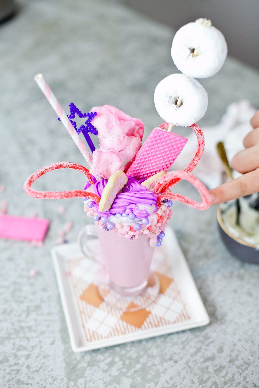 These Epic Royal Crazy shakes are indulgently MAGICAL! A rich, thick strawberry milkshake is topped with a sugaring of sprinkles and candies to make a delicious crazy shake drink fit for a princess... or a prince. A pretty in pink and purple freak shake!