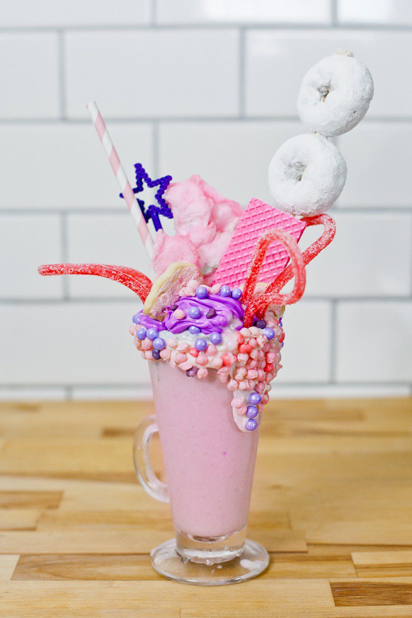 These Epic Royal Crazy shakes are indulgently MAGICAL! A rich, thick strawberry milkshake is topped with a sugaring of sprinkles and candies to make a delicious crazy shake drink fit for a princess... or a prince. A pretty in pink and purple freak shake!
