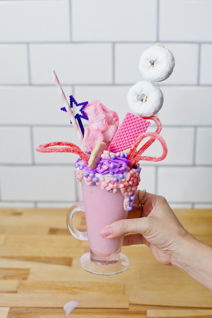 These Epic Royal Crazy shakes are indulgently MAGICAL! A rich, thick strawberry milkshake is topped with a sugaring of sprinkles and candies to make a delicious crazy shake drink fit for a princess... or a prince. A pretty in pink and purple freak shake!