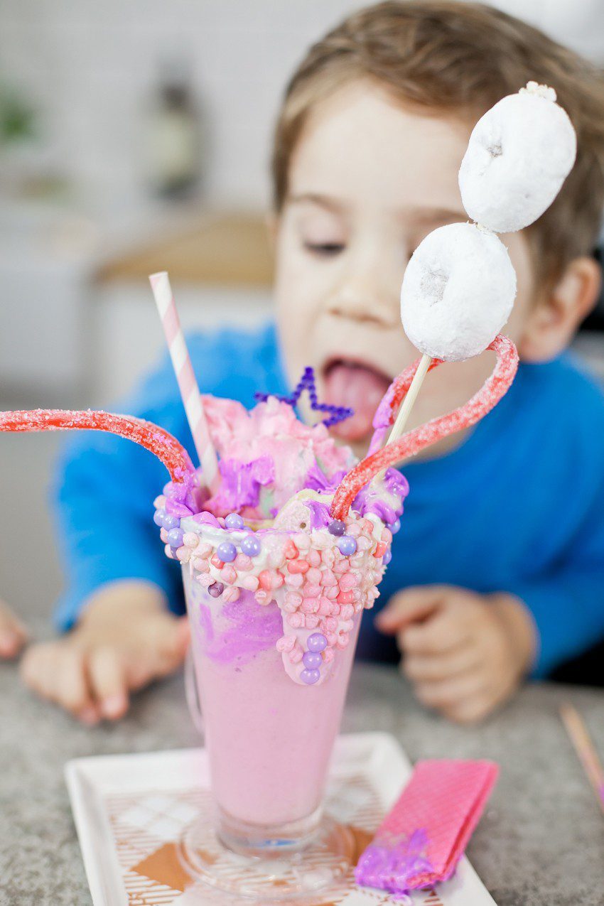 These Epic Royal Crazy shakes are indulgently MAGICAL! A rich, thick strawberry milkshake is topped with a sugaring of sprinkles and candies to make a delicious crazy shake drink fit for a princess... or a prince. A pretty in pink and purple freak shake!
