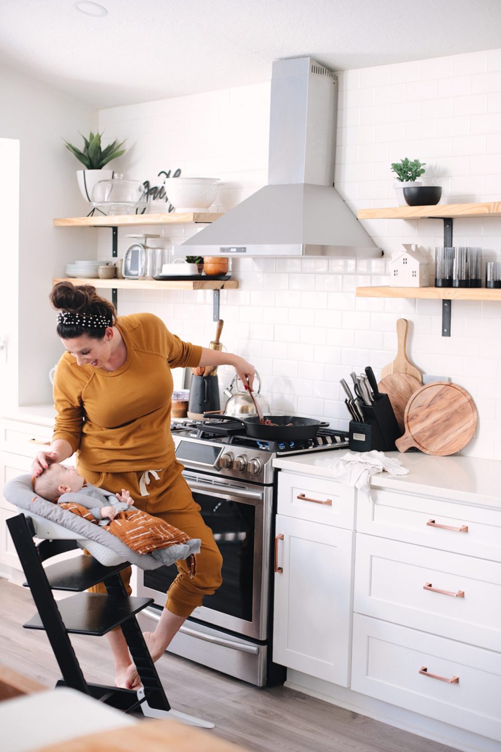 Avocado Keto Taco Bowls recipe featured by top Florida lifestyle blog, Fresh Mommy Blog: Cooking in the farmhouse kitchen with baby. Newborn baby in the black stokke tripp trapp high chair | Keto Taco Bowls by popular Florida lifestyle blog, Fresh Mommy Blog: image of a mom cooking meat at her stove with her baby next to her in a Stokke tripp trapp high chair.