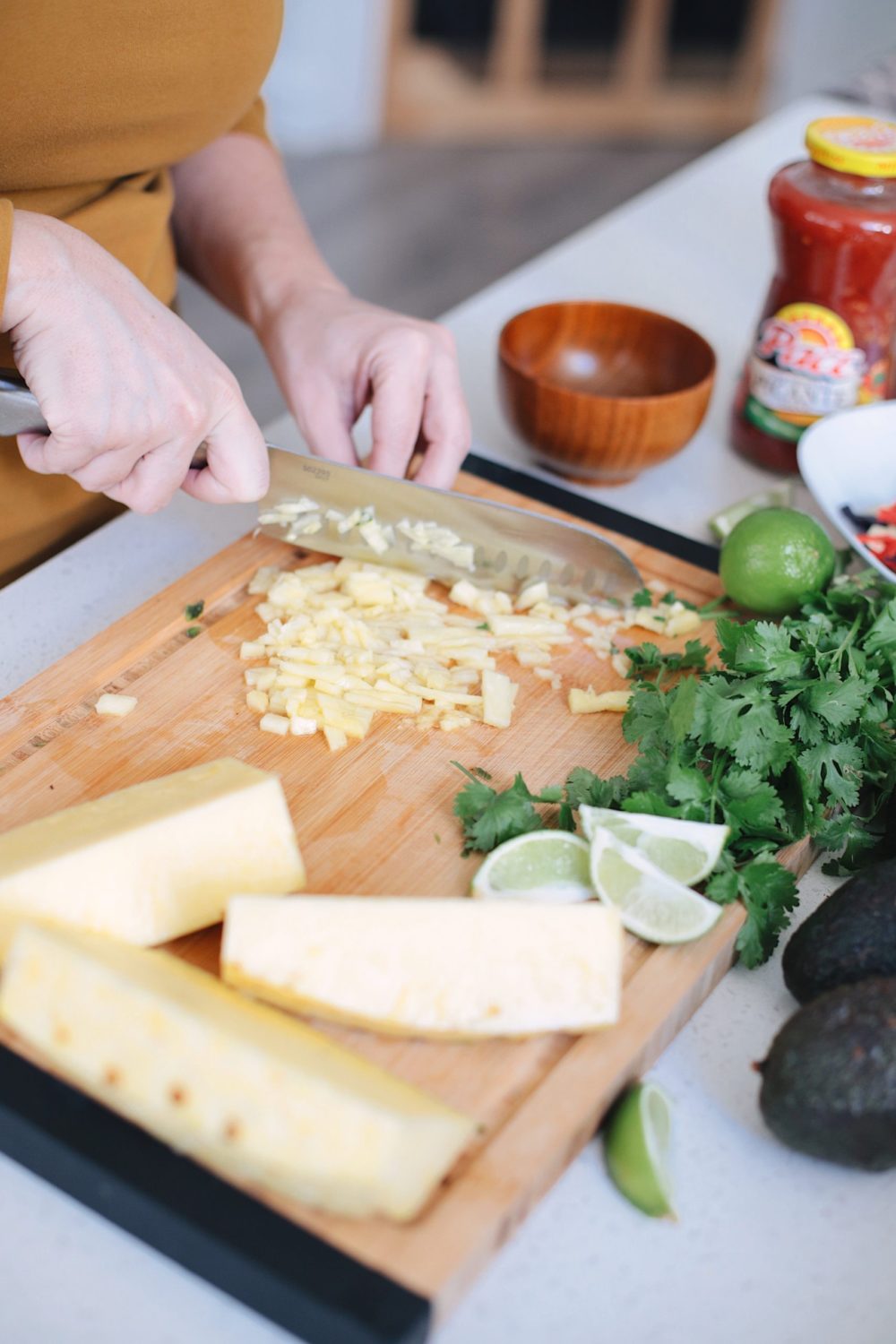 Avocado Keto Taco Bowls recipe featured by top Florida lifestyle blog, Fresh Mommy Blog: Chopped pineapple for the best taco bowl, a delicious twist for taco night | Keto Taco Bowls by popular Florida lifestyle blog, Fresh Mommy Blog: image of a woman chopping pineapple on a cutting board.