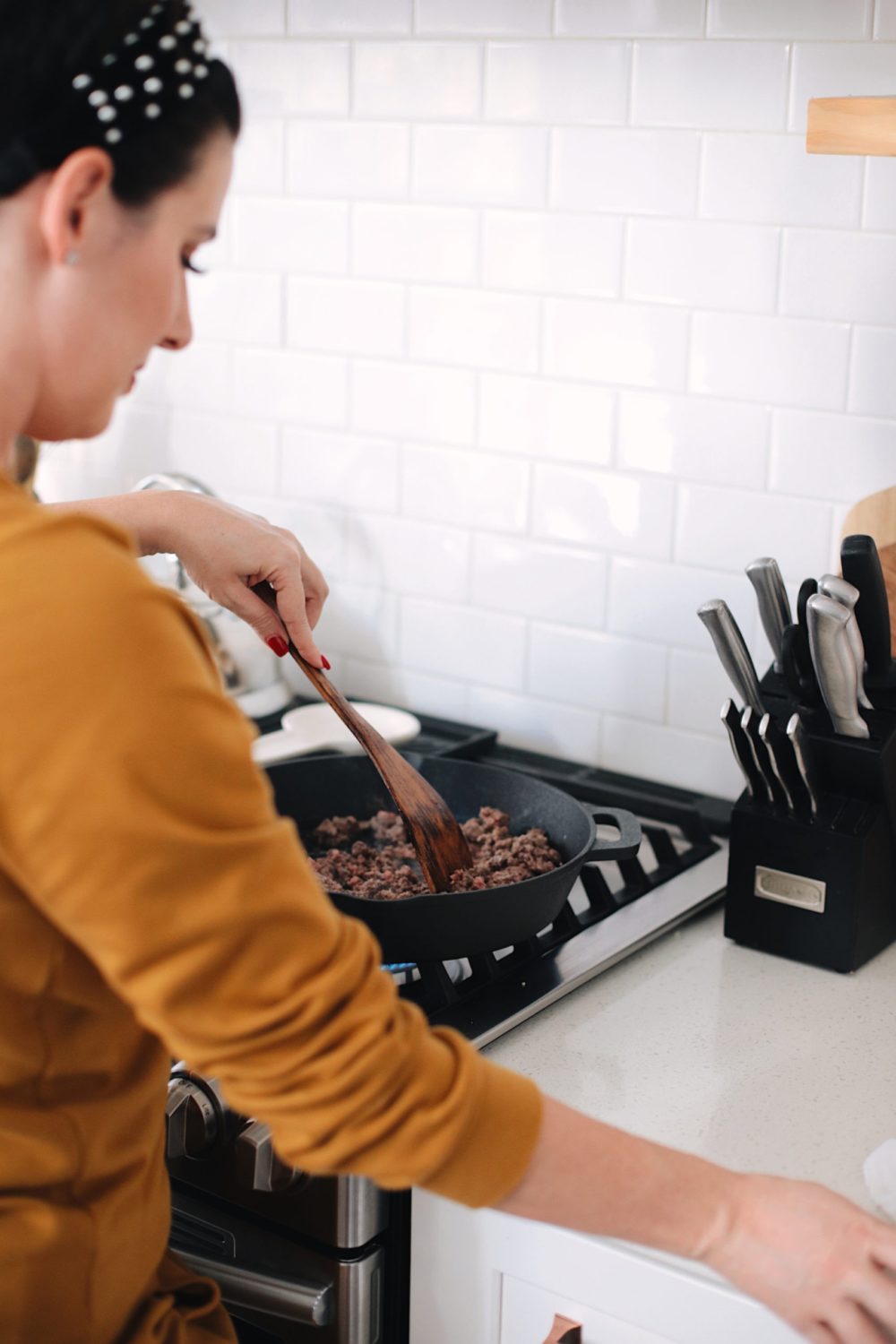 Avocado Keto Taco Bowls recipe featured by top Florida lifestyle blog, Fresh Mommy Blog: The best ever taco meat recipe with homemade taco seasoning | Keto Taco Bowls by popular Florida lifestyle blog, Fresh Mommy Blog: image of a woman cooking meat at her gas range stove.