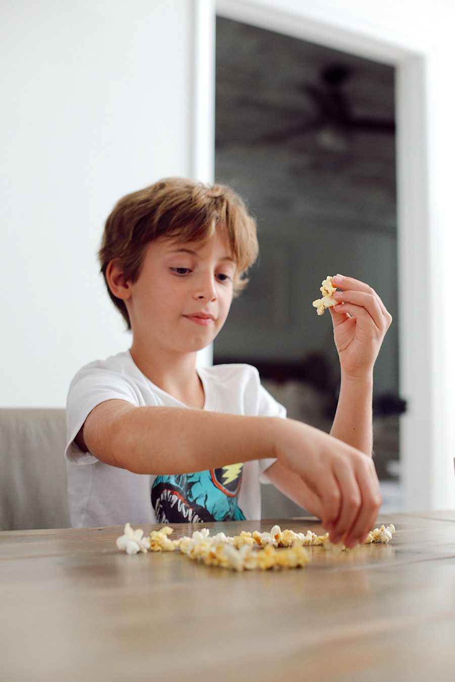 Popcorn charades and more popcorn games for family game night! | Family Fun Night by popular Florida lifestyle blog, Fresh Mommy Blog: image of a boy making a shape on a table out of popcorn. 