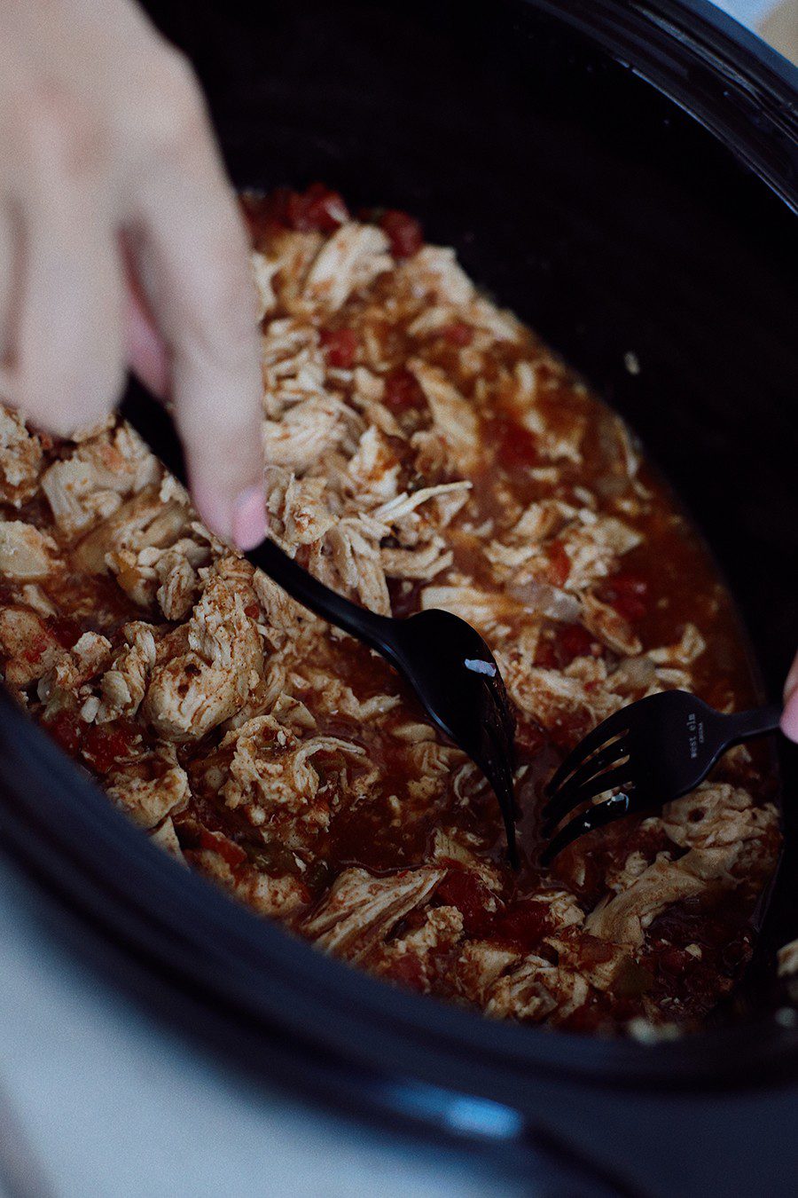 How to make an epic taco board and taco party platter tips! Plus, the best slow cooker taco chicken recipe!  | Chicken Tacos by popular Florida lifestyle blog, Fresh Mommy Blog: image of a woman shredding chicken in a slow cooker. 
