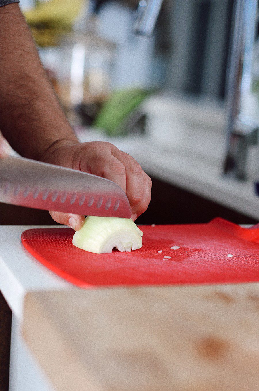 How to make an epic taco board and taco party platter tips! Plus, the best slow cooker taco chicken recipe! | Chicken Tacos by popular Florida lifestyle blog, Fresh Mommy Blog: image of a man chopping a white onion on a red cutting board. 